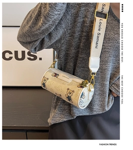 Détails de la large bandoulière logo et motif ours sur un sac cylindrique tendance