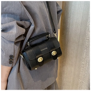 Détail d'un sac à bandoulière noir effet crocodile avec boucles dorées et texte fashion