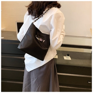 Detailansicht einer schwarzen Oxford-Stofftasche mit Lucky-Stickerei und Kettenriemen am Modell