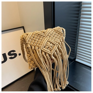 Close-up of bohemian beige straw bag with geometric weave patterns and long fringes
