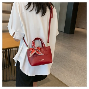 Detail of dark red leather handbag with fashion lettering and plaid silk scarf handle