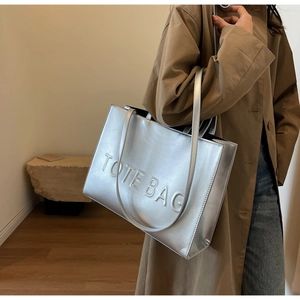 Vue macro du sac cabas argenté avec lettrage TOTE BAG en relief et texture métallique