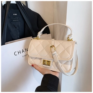 Dettaglio della borsa beige trapuntata con chiusura a scatto dorata e texture in pelle