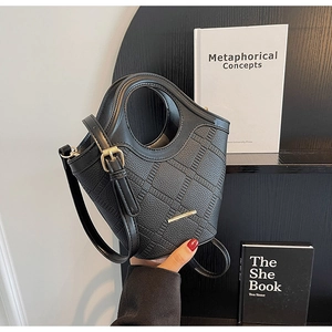 Détail du sac seau en cuir noir matelassé avec poignée ronde et garniture dorée