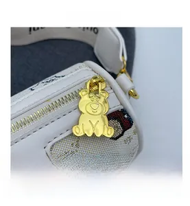 Détail de la fermeture éclair ours doré et sac cylindrique blanc en cuir premium