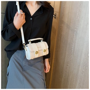Détail d'un sac à main crème effet crocodile avec boucles dorées et texte de mode