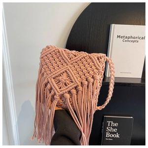 Detail of pink handmade macramé straw bag featuring geometric patterns and long fringes