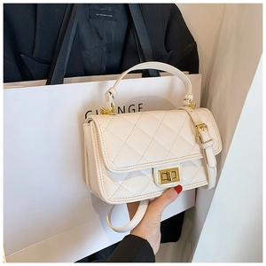 Dettaglio della piccola borsa bianca trapuntata con chiusura a rotazione dorata di lusso