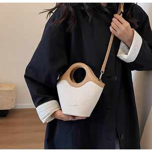 Détail de la texture cuir blanc sur le mini sac seau avec anse ronde marron
