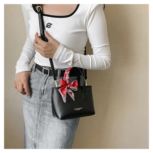 Detail of black mini bucket bag with silk scarf bow and gold fashion lettering