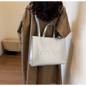 Détail d'un sac cabas argenté métallisé avec lettrage TOTE BAG embossé en relief