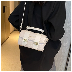Détail d'un sac à main beige à texture crocodile avec fermoirs dorés et bandoulière