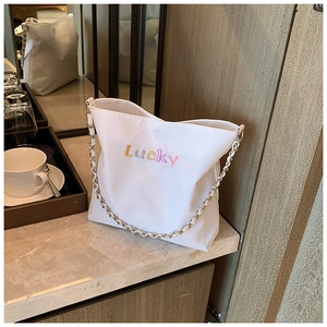 Detail einer weißen Nylon-Beuteltasche mit Lucky-Stickerei und Metallkettenriemen