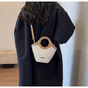 Sac seau matelassé tendance en beige et cuir camel porté par un mannequin