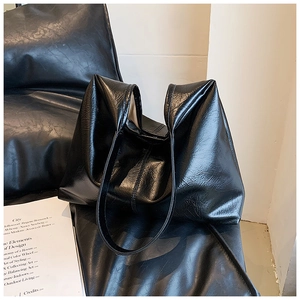 Détail d'un sac cabas noir brillant montrant sa texture plissée et ses fines lanières