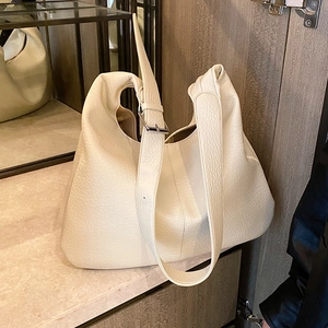 Minimalist cream white hobo bucket bag with pebbled leather texture and adjustable strap