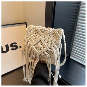 Detail of bohemian handmade beige woven macrame bag with geometric patterns and long tassels