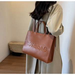 Sac fourre-tout marron en similicuir avec lettrage embossé porté par un mannequin