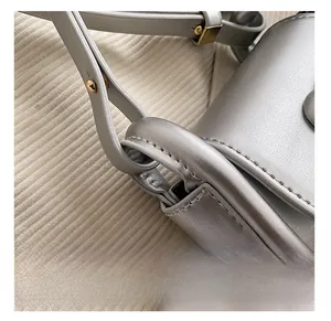Detail showing high-quality golden metal hardware and fine stitching on a silver saddle bag