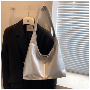 Détail d'un sac hobo argenté texturé avec finition métallique sur un blazer noir