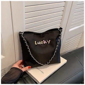 Detail der Oxford-Stoff Beuteltasche mit Lucky-Schriftzug und Metallkettenriemen auf Buch