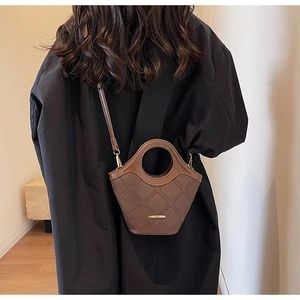 Détail du sac seau en cuir marron foncé avec motif matelassé et poignée ronde
