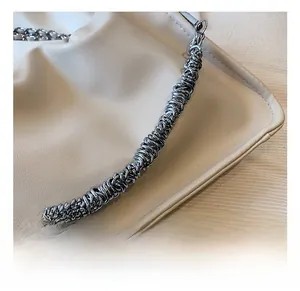Detailed close-up of premium silver spiral metal chain on cream leather handbag