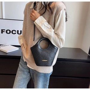 Détail d'un sac seau en cuir matelassé noir avec barre dorée et poignée circulaire unique