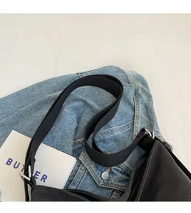 Détail du sac bandoulière en toile noire avec sangle réglable sur veste en jean bleu