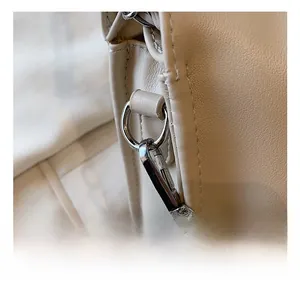 Detail view of the elegant beige cloud bag featuring silver metal hooks and chain strap