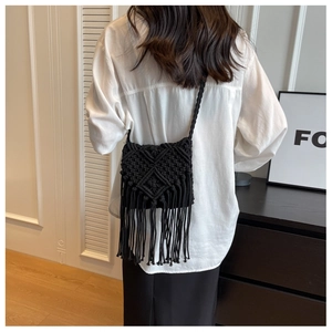 Detail of handmade black macrame bag with woven diamond patterns and long bohemian tassels