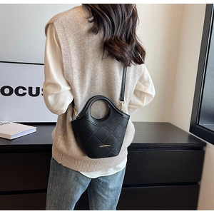 Détail du sac seau en cuir grainé noir avec ferrures dorées et poignée ronde