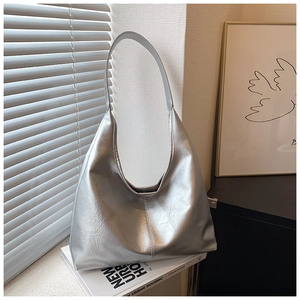 Détail d'un sac hobo argenté métallisé en similicuir posé sur des magazines de mode