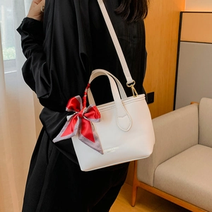 White leather bucket handbag with red plaid bow tie and golden text on front strap