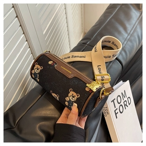 Détail du sac cylindre Boston avec broderie ours et large bandoulière en tissu amovible