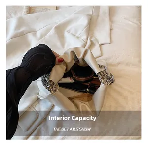 Detail showing white cloud bag interior capacity with silver chain and cosmetics