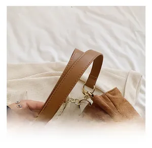 Detail of reinforced brown suede handles with golden metal ring on a tote bag