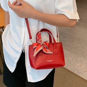 Chic red leather bucket bag with silk scarf handle and golden fashion typography