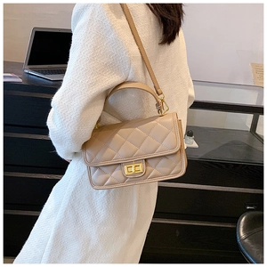 Dettaglio della borsa a tracolla trapuntata beige con chiusura dorata su una modella