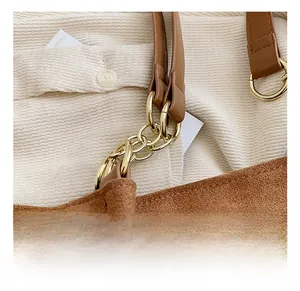 Macro shot of gold metal hardware connector and brown suede strap on a tote bag