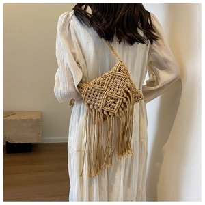 Detail of bohemian straw shoulder bag with long fringe tassels and woven geometric pattern