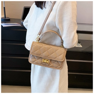 Dettaglio della borsa beige trapuntata con chiusura dorata e manico superiore rigido