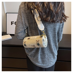 Détail du sac cylindrique blanc avec imprimé ours et large bandoulière à logo