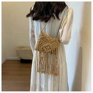 Detail of bohemian straw crossbody bag featuring intricate diamond weave and long tassels