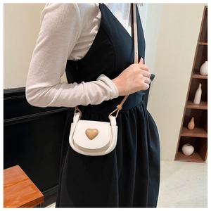 Detailed shot of mini cream crossbody bag with brown heart motif on model