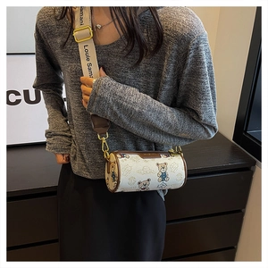 Détail du sac cylindrique crème avec imprimé ours en peluche et large bandoulière en toile