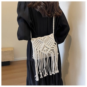 Detail of white macrame woven bag with long tassels and geometric knit pattern