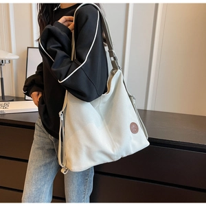 Vue portée d'un grand sac hobo en toile crème avec logo en cuir et bandoulière réglable
