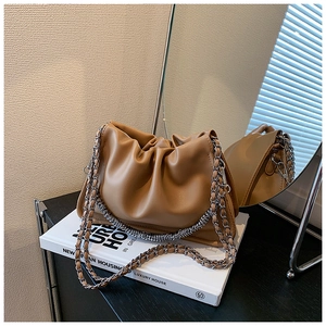 Detailed macro of a pleated cloud bag in camel brown with silver metal chain strap