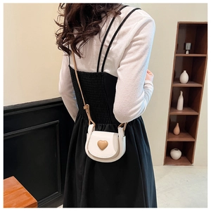 Detailed shot of a beige mini saddle bag featuring a yellow heart-shaped ornament